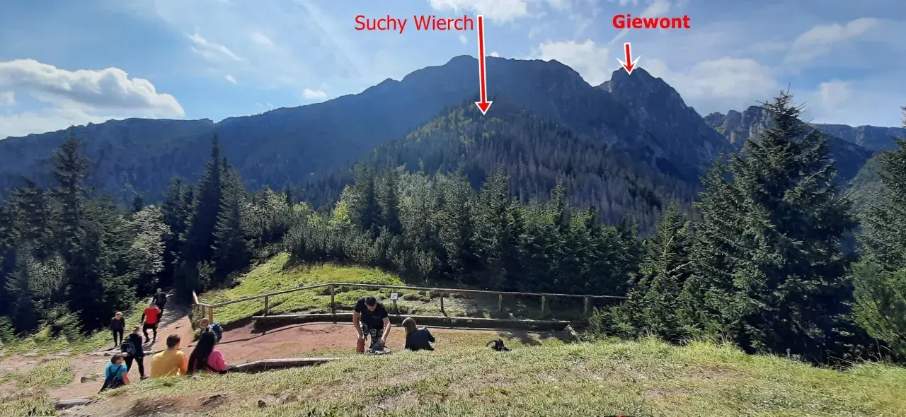 Widok na Suchy Wierch i Giewont z początku szlaku w Dolinie Strążyskiej. Turyści odpoczywają na ścieżce.