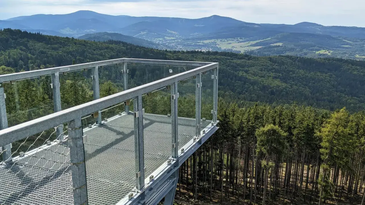 Widok z tarasu widokowego na górze Trojak w Lądku-Zdroju. Rozległe lasy i góry w tle.