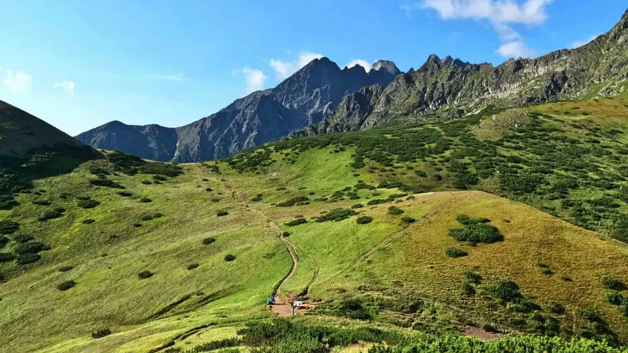 Malownicze Tatry Bielskie z krętą ścieżką wijącą się po zielonych zboczach. W oddali skaliste szczyty.