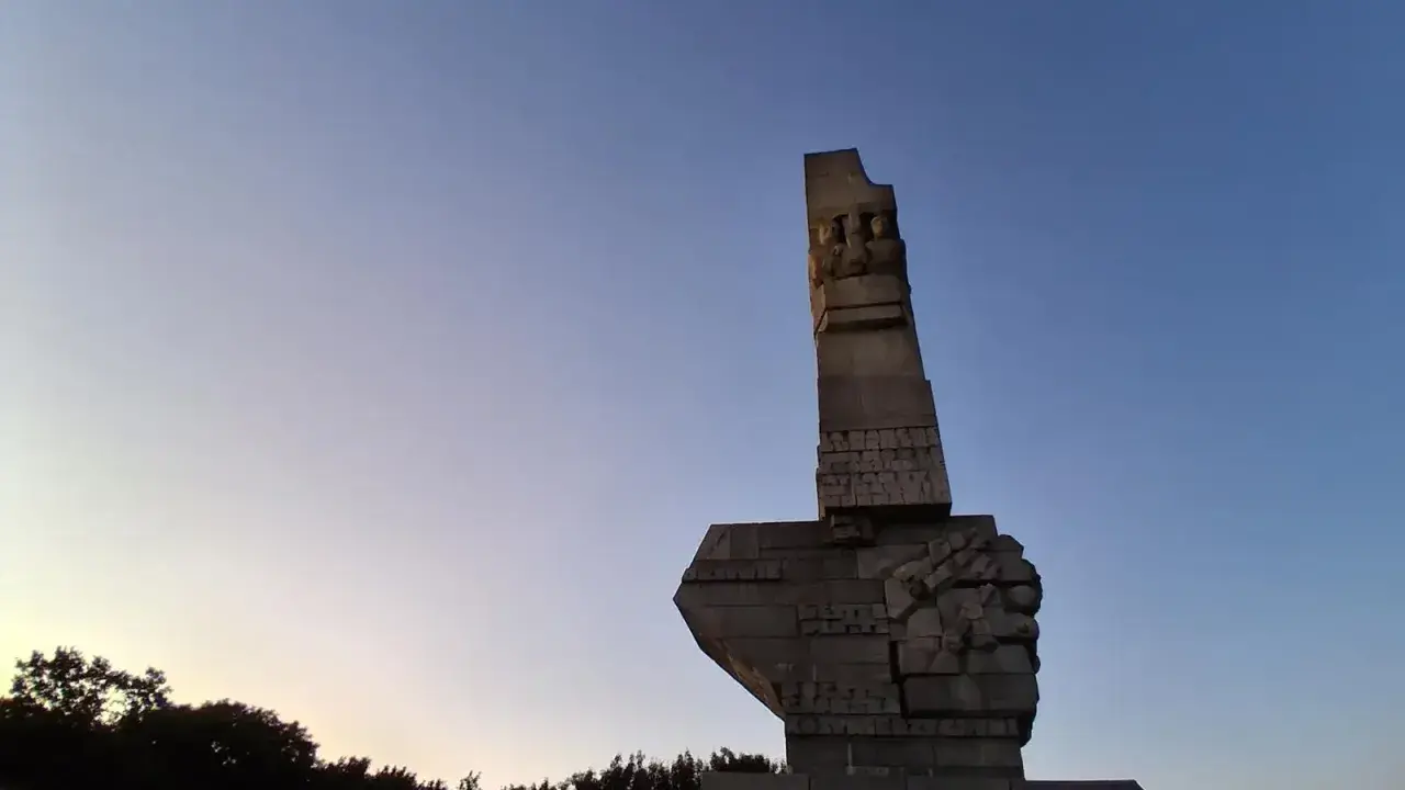 Pomnik Obrońców Wybrzeża na Westerplatte w Gdańsku, majestatyczny symbol bohaterstwa, na tle błękitnego nieba o zmierzchu.