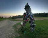 Skopiec szlak. Rzeźba z butów na rozstaju dróg, w tle zachodzące słońce i góry.