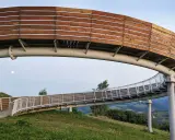 Drewniana kładka widokowa wznosi się nad zielonymi wzgórzami, oferując panoramę jak z **Woli Kroguleckiej**. Księżyc w pełni towarzyszy spacerowiczom.