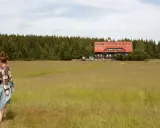 Dziewczyna w kratę podziwia schronisko na tle lasu w Górach Izerskich, Polska.