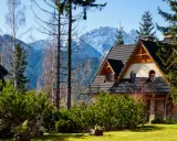 Górski krajobraz z domem w stylu zakopiańskim. Idealne miejsce na jednodniowe zakopane atrakcje, z widokiem na ośnieżone szczyty Tatr.