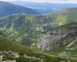 Malownicza trasa w Kościelisku. Zielone zbocza górskie, skaliste urwisko i pasma górskie w oddali tworzą zapierający dech w piersiach krajobraz.
