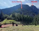 Widok na Suchy Wierch i Giewont z początku szlaku w Dolinie Strążyskiej. Turyści odpoczywają na ścieżce.