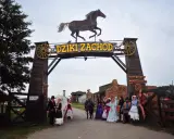 Park rozrywki Dziki Zachód koło Kołobrzegu. Grupa osób w strojach z Dzikiego Zachodu pozuje przed bramą.