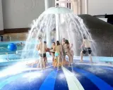 Radość w aquaparku lubuskie! Grupa ludzi bawi się pod parasolem wodnym, ciesząc się orzeźwiającą kąpielą.