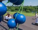 Tarnów atrakcje dla dzieci: dwie kobiety siedzą na drewnianym tarasie, a mała dziewczynka w letniej sukience i kapeluszu pozuje do zdjęcia.