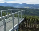 Widok z tarasu widokowego na górze Trojak w Lądku-Zdroju. Rozległe lasy i góry w tle.