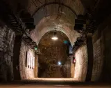 Wnętrze tunelu w Górach Sowich. Betonowe ściany, łukowe sklepienie i oświetlenie tworzą mroczny klimat.
