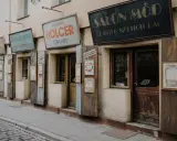 Urokliwe szyldy sklepów w Kazimierzu w Krakowie: "Salon Mód", "Holcer Stolorz", "Stanisław Nowak Sklep Spożywczy" i inne.