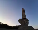 Pomnik Obrońców Wybrzeża na Westerplatte w Gdańsku, majestatyczny symbol bohaterstwa, na tle błękitnego nieba o zmierzchu.