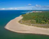 Piękna plaża i las na Helu. W oddali widać miasteczko i port, idealne miejsce na wakacyjne atrakcje.