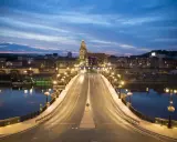 Most w Gorzowie Wielkopolskim nocą, oświetlony latarniami, z widokiem na miasto i wieżę kościelną. Atrakcje miasta w wieczornym blasku.