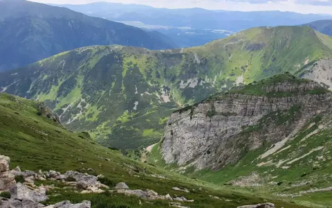 Malownicza trasa w Kościelisku. Zielone zbocza górskie, skaliste urwisko i pasma górskie w oddali tworzą zapierający dech w piersiach krajobraz.