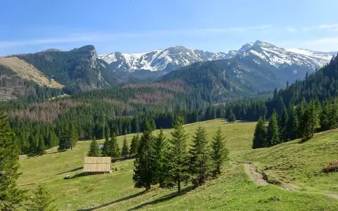 Piękne trasy Tatry. Zielone hale, lasy i ośnieżone szczyty. Drewniana chata i ścieżka zapraszają do wędrówki.