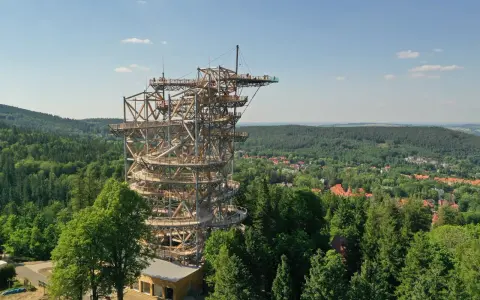 Drewniana konstrukcja Sky Walk w Świeradowie-Zdroju wznosi się ponad lasem, oferując widok na okoliczne wzgórza i miasteczko.