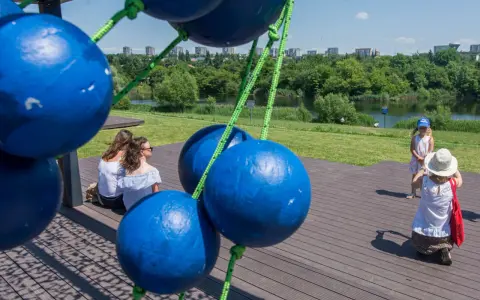 Tarnów atrakcje dla dzieci: dwie kobiety siedzą na drewnianym tarasie, a mała dziewczynka w letniej sukience i kapeluszu pozuje do zdjęcia.