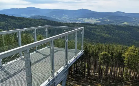 Widok z tarasu widokowego na górze Trojak w Lądku-Zdroju. Rozległe lasy i góry w tle.