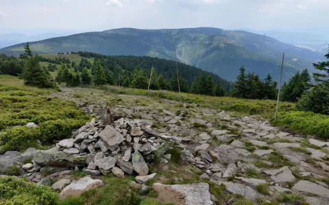 Kamienny szlak prowadzi przez zielone zbocza masywu Śnieżnika. W oddali widać kolejne pasma górskie.