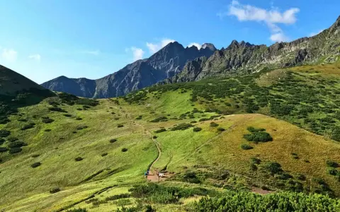 Malownicze Tatry Bielskie z krętą ścieżką wijącą się po zielonych zboczach. W oddali skaliste szczyty.