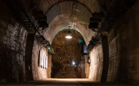 Wnętrze tunelu w Górach Sowich. Betonowe ściany, łukowe sklepienie i oświetlenie tworzą mroczny klimat.