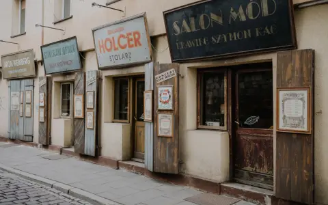 Urokliwe szyldy sklepów w Kazimierzu w Krakowie: "Salon Mód", "Holcer Stolorz", "Stanisław Nowak Sklep Spożywczy" i inne.