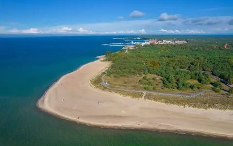 Piękna plaża i las na Helu. W oddali widać miasteczko i port, idealne miejsce na wakacyjne atrakcje.