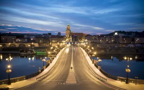 Most w Gorzowie Wielkopolskim nocą, oświetlony latarniami, z widokiem na miasto i wieżę kościelną. Atrakcje miasta w wieczornym blasku.
