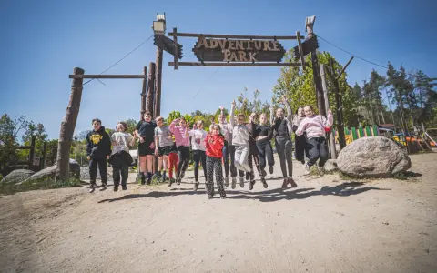 Radosna grupa dzieci skacze przed bramą "Adventure Park" w Gdyni.