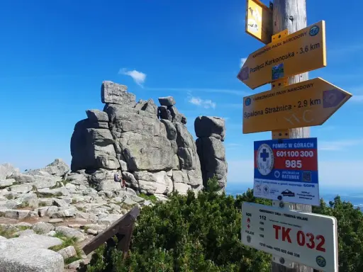 Skaliste szczyty w Karkonoszach, drogowskazy turystyczne i tablica z numerami alarmowymi. Słonecznik karkonosze.