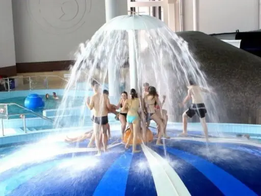 Radość w aquaparku lubuskie! Grupa ludzi bawi się pod parasolem wodnym, ciesząc się orzeźwiającą kąpielą.