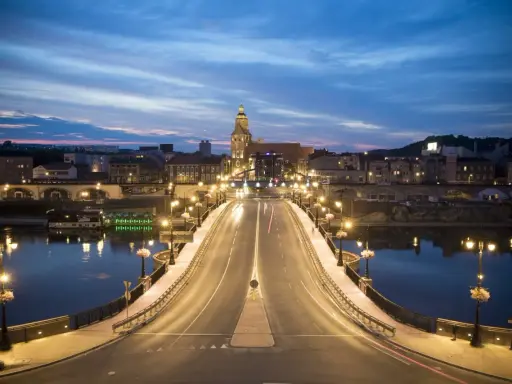 Most w Gorzowie Wielkopolskim nocą, oświetlony latarniami, z widokiem na miasto i wieżę kościelną. Atrakcje miasta w wieczornym blasku.
