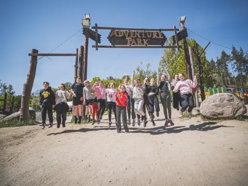 Radosna grupa dzieci skacze przed bramą "Adventure Park" w Gdyni.