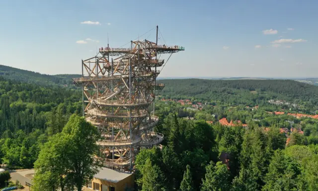 Drewniana konstrukcja Sky Walk w Świeradowie-Zdroju wznosi się ponad lasem, oferując widok na okoliczne wzgórza i miasteczko.