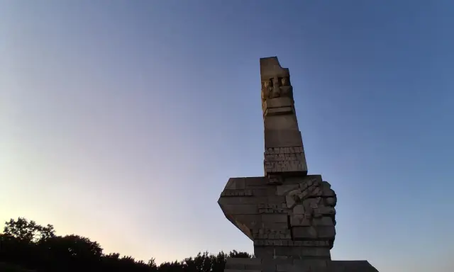 Pomnik Obrońców Wybrzeża na Westerplatte w Gdańsku, majestatyczny symbol bohaterstwa, na tle błękitnego nieba o zmierzchu.