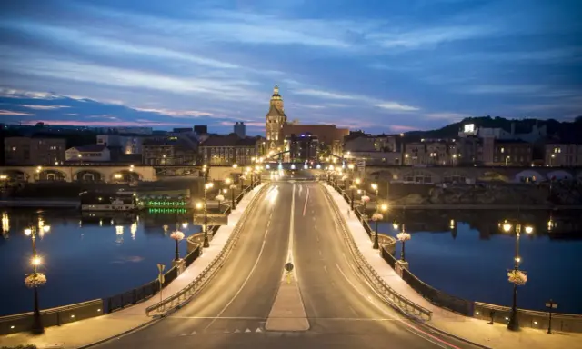Most w Gorzowie Wielkopolskim nocą, oświetlony latarniami, z widokiem na miasto i wieżę kościelną. Atrakcje miasta w wieczornym blasku.