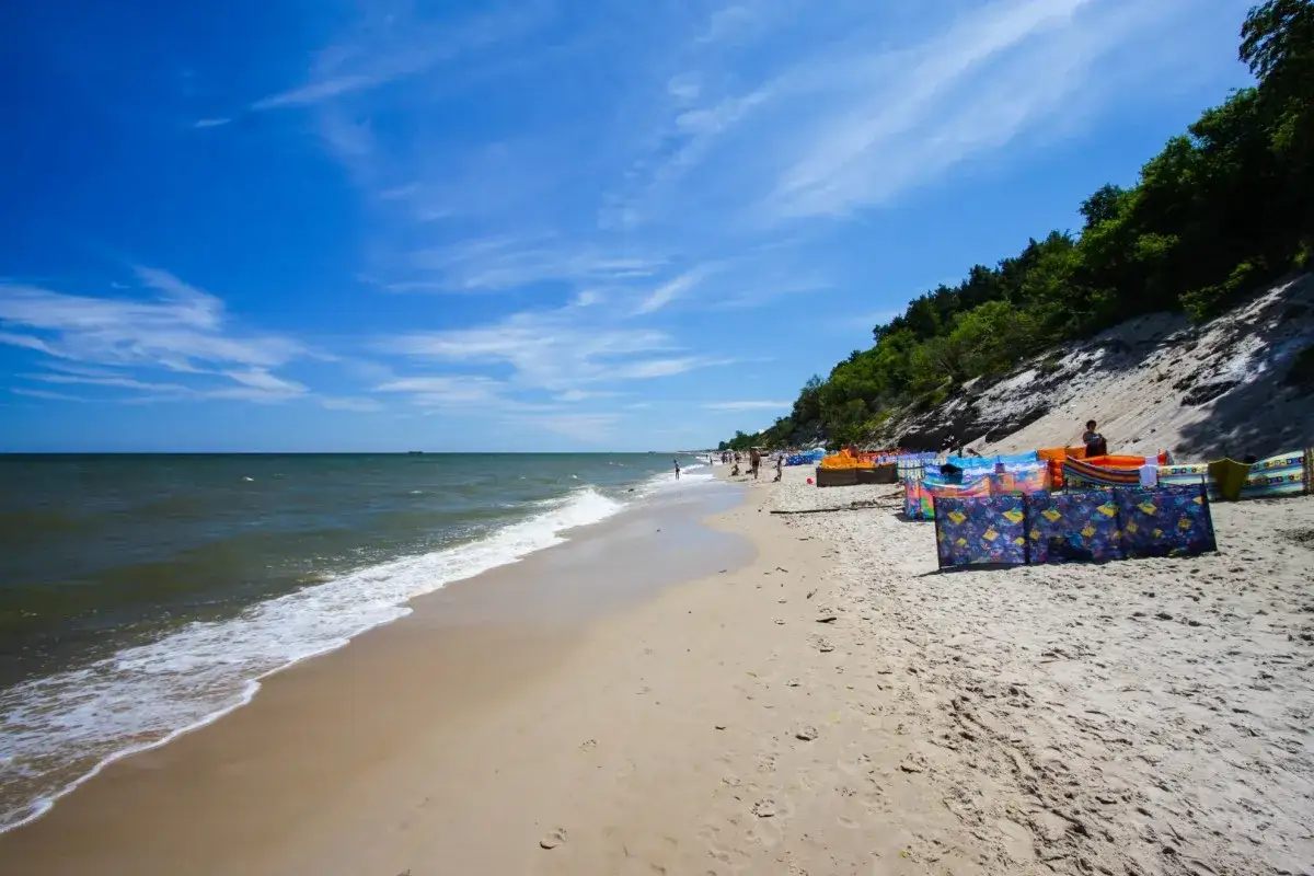 Słoneczna plaża w Chłapowie z kolorowymi parawanami, idealne miejsce na rodzinne wakacje i chwile relaksu.