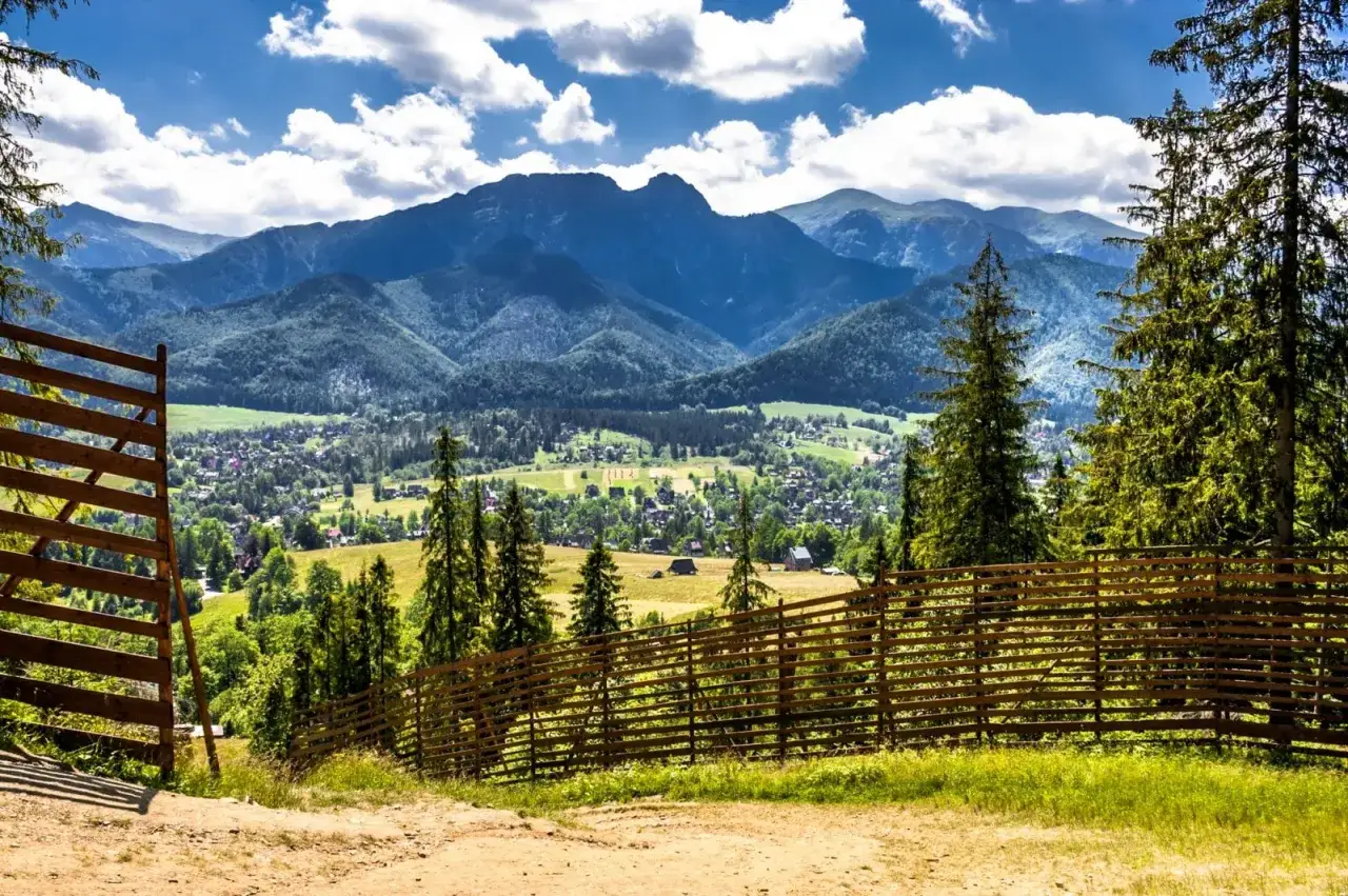 Malowniczy widok na Tatry, idealne miejsce na atrakcje w górach dla dzieci. Drewniane ogrodzenie i zielone łąki zapraszają do odkrywania.