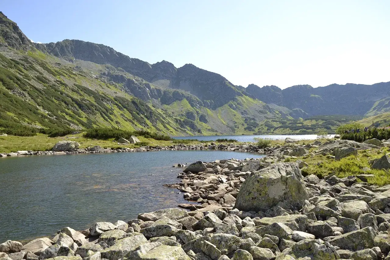 Malownicze jezioro w Tatrach, idealne na jedne z wielu szlak&oacute;w turystycznych Zakopane. Kamieniste brzegi i strome zbocza g&oacute;r.