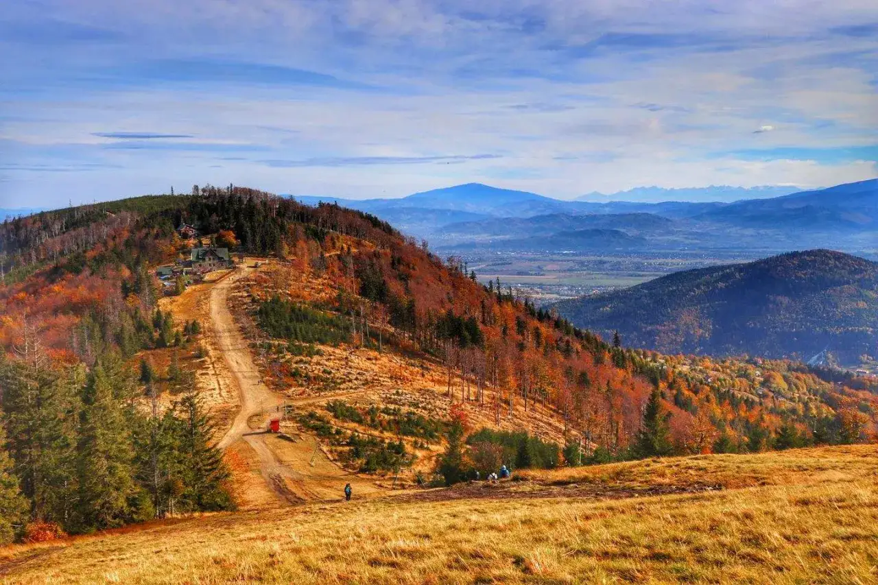 Jesienna panorama Beskid&oacute;w z widokiem na g&oacute;rskie schronisko i krętą ścieżkę. Odkryj najpiękniejsze szlaki w Beskidach.