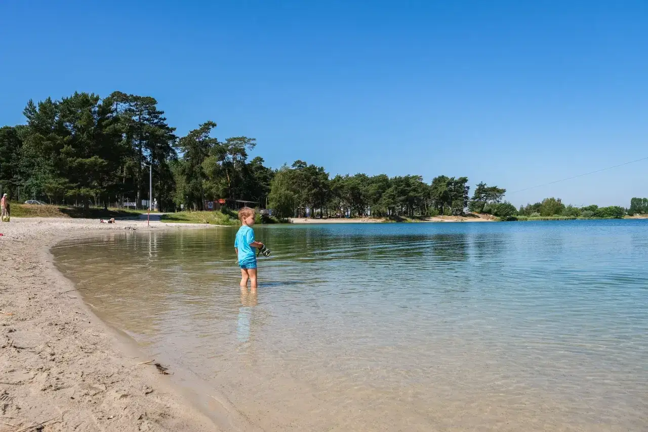 Chłopiec w wodzie na piaszczystej plaży. Piękne kąpieliska Małopolska zapraszają do wypoczynku nad czystą, błękitną wodą.