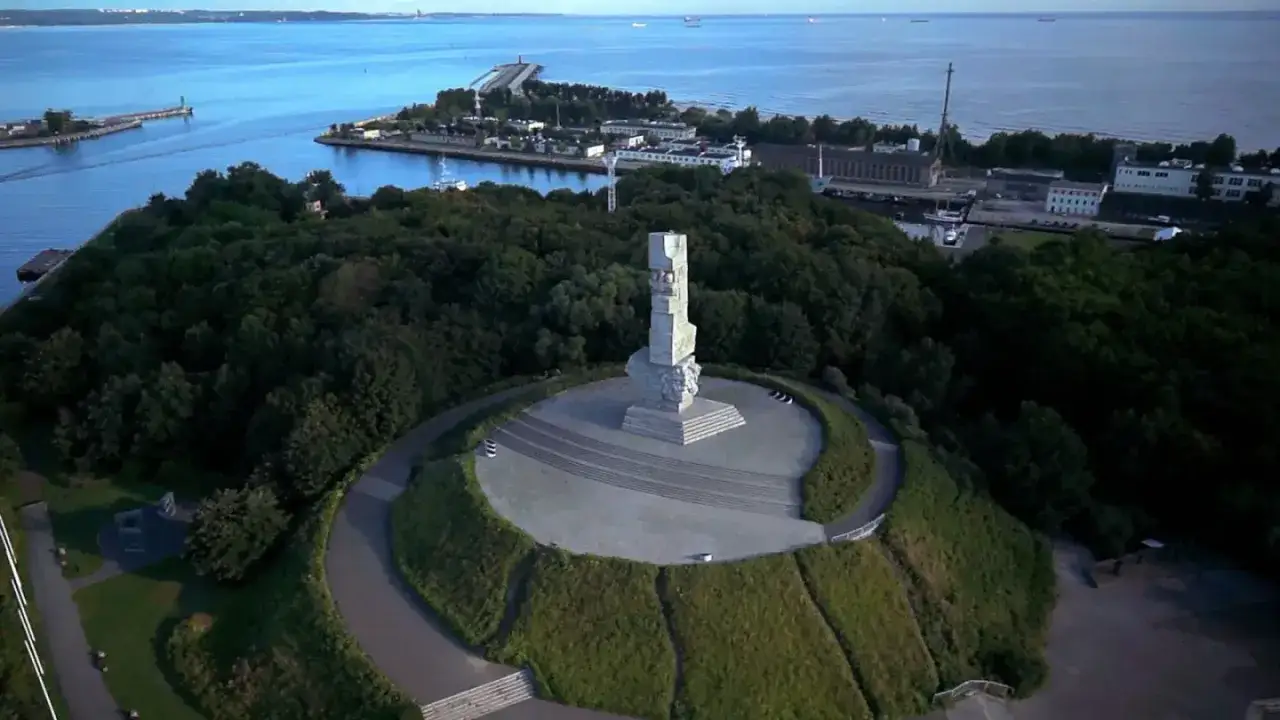Pomnik Obrońc&oacute;w Wybrzeża na Westerplatte, otoczony zielenią, g&oacute;ruje nad Zatoką Gdańską.