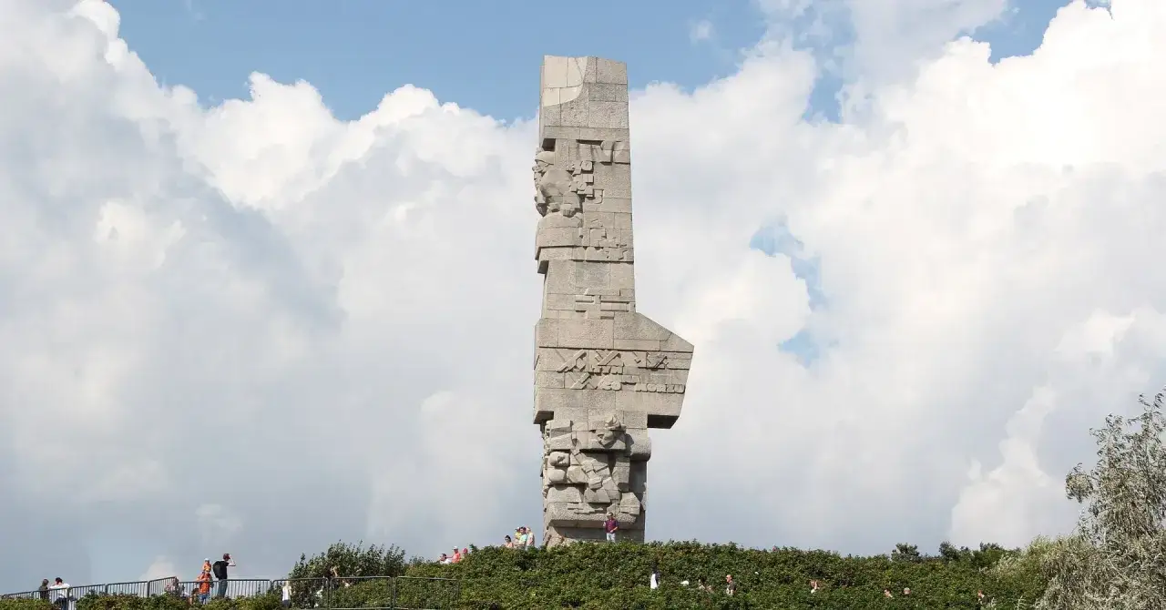 Pomnik Obrońców Wybrzeża na Westerplatte w Gdańsku, z turystami na tle nieba.